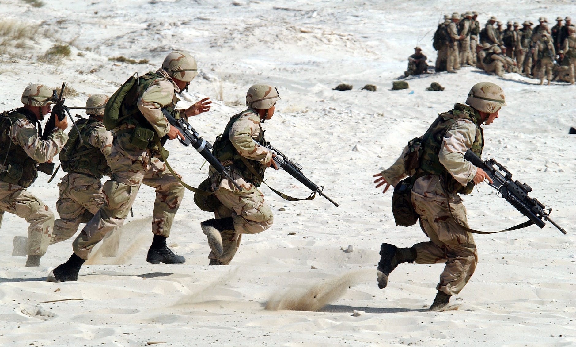 A photo of soldiers with guns running into battle.